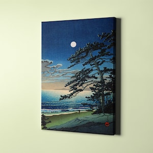 Puede incluir: Una impresi&oacute;n en lienzo de una serena escena costera nocturna. La obra representa una luna llena en un cielo azul oscuro, un pino silueteado y una playa de arena con suaves olas. La paleta de colores incluye azules, verdes y blancos.