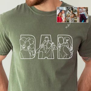 May include: Olive green t-shirt with the word "DAD" in white outline letters. Each letter features a line drawing of a parent with a child. Three small color photos of parents and children are in the upper right corner.