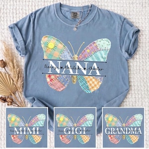 May include: A light blue t-shirt featuring a colorful patchwork butterfly design. The butterfly has a sun accent and the word "NANA" in black script, with names below. Additional designs with "MIMI", "GIGI", and "GRANDMA" are shown.