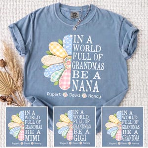 May include: A light blue t-shirt with the text "IN A WORLD FULL OF GRANDMAS BE A NANA" and a colorful flower design. The flower petals are patterned with polka dots and gingham. The names Rupert, David, and Nancy are below the text.