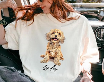 Peut inclure: Sweat-shirt crème avec une illustration détaillée d'un chien brun et beige avec des poils bouclés. Le chien est assis, la langue sortie. Le nom "Bailey" est écrit en cursive en dessous du chien.