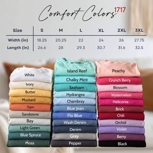 May include: A size chart for Comfort Colors 1717 t-shirts with width and length measurements in inches for sizes S through 3XL, displayed above three vertical stacks of folded t-shirts in various colors including white, blue, pink, and black.