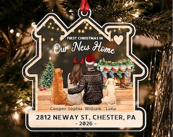 May include: A house-shaped Christmas ornament featuring an illustration of two people and two dogs sitting by a fireplace. Text reads: FIRST CHRISTMAS IN Our New Home, Cooper, Sophia, William, Luna, 2812 NEWAY ST, CHESTER, PA - 2026 -.