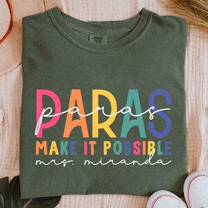 May include: A green t-shirt with the text "paras make it possible mrs. miranda" in rainbow colors.