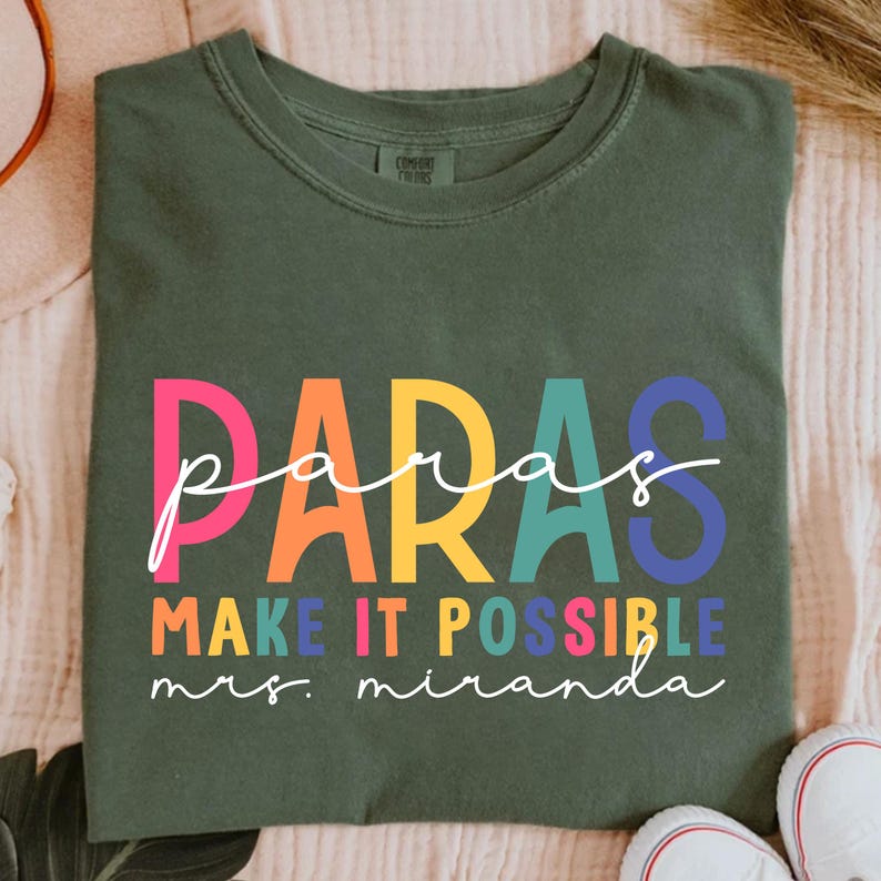 May include: A green t-shirt with the text "paras make it possible mrs. miranda" in rainbow colors.
