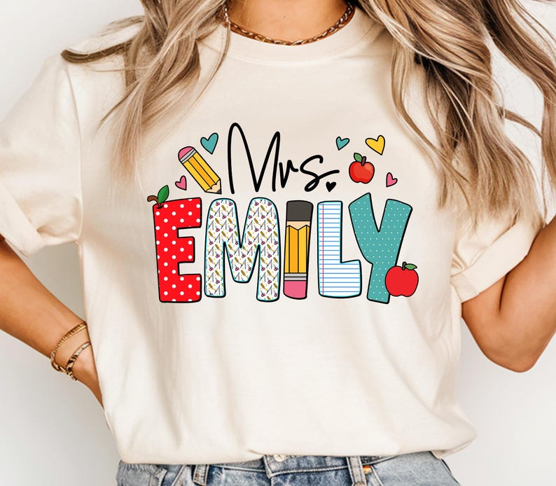 May include: A white t-shirt with the text "Mrs. Emily" in colorful letters with a pencil, apple, and heart designs.