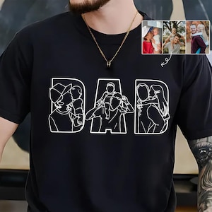 Peut inclure: T-shirt noir avec le mot "DAD" en blanc, chaque lettre repr&eacute;sentant un dessin au trait d'un parent avec un enfant. Comprend un petit encart de trois photos en couleur de parents et d'enfants.