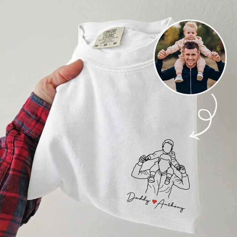 May include: White Comfort Colors t-shirt with a line drawing of a person carrying a child on their shoulders. The text "Daddy ❤️ Anthony" is below the drawing. A circular photo of a person with a child is in the upper right corner.