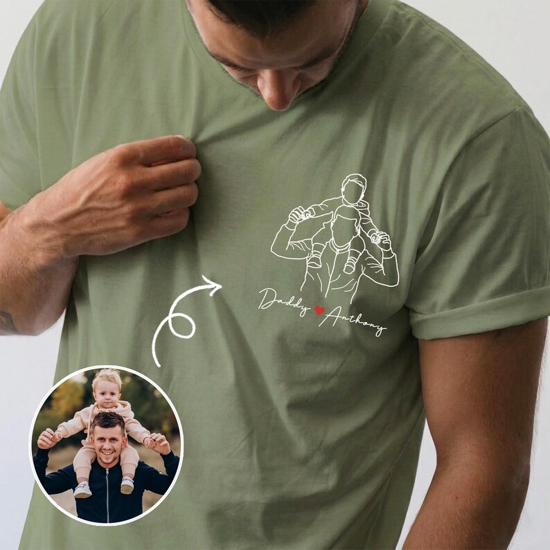 May include: Olive green t-shirt featuring a line drawing of a person carrying a child on their shoulders, with the text "Daddy Anthony" and a heart. A circular photo of a person with a child is in the lower left corner.