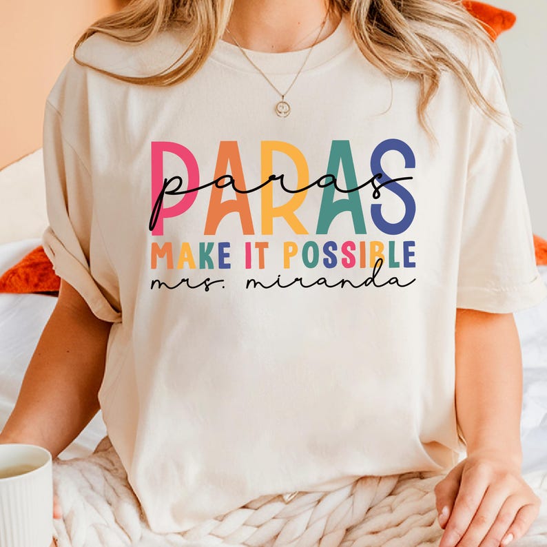 May include: A white t-shirt with a rainbow colored graphic that says "paras make it possible mrs. miranda".