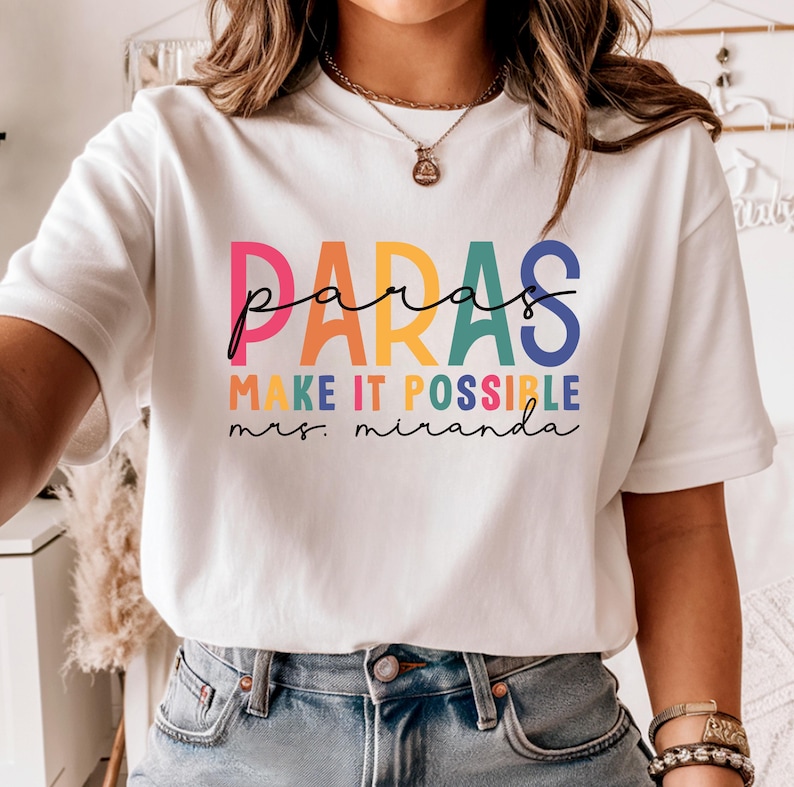 May include: White t-shirt with a rainbow colored graphic that says "paras make it possible mrs. miranda".