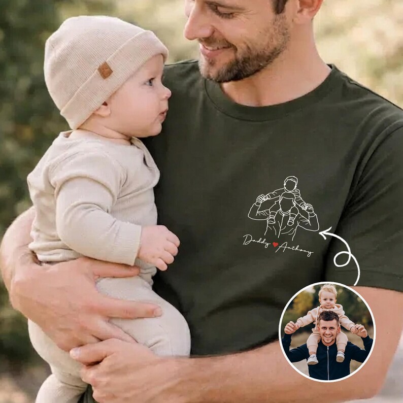 May include: An olive green t-shirt featuring a line drawing of a father carrying a child on his shoulders, with the text "Daddy Anthony". A baby in a beige outfit and hat is held by a man. A small photo of a father and child is in the lower right corner.
