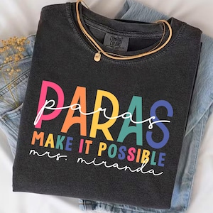 May include: A black t-shirt with the text "paras make it possible mrs. miranda" in rainbow colors.