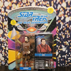 May include: A Star Trek: The Next Generation action figure of Lore, in its original packaging. The figure is brown and tan, with a detailed uniform. The packaging features the Star Trek logo and a picture of Lore.