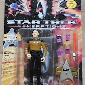 Könnte beinhalten: Star Trek Generations Actionfigur von Lieutenant Commander Data, Second Officer der U.S.S. Enterprise. Die Figur befindet sich in einer transparenten Kunststoffverpackung mit Zubehör, darunter ein Phaser und ein Starfleet-Abzeichen. Die Verpackung enthält den Text "Exclusive Mini Star Trek Generations Movie Poster Included!"