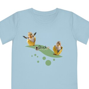 May include: A light blue t-shirt with a graphic of two baby ducks wearing yellow raincoats. The ducks are on a green path with the text "Duck Cloud" in a circle.