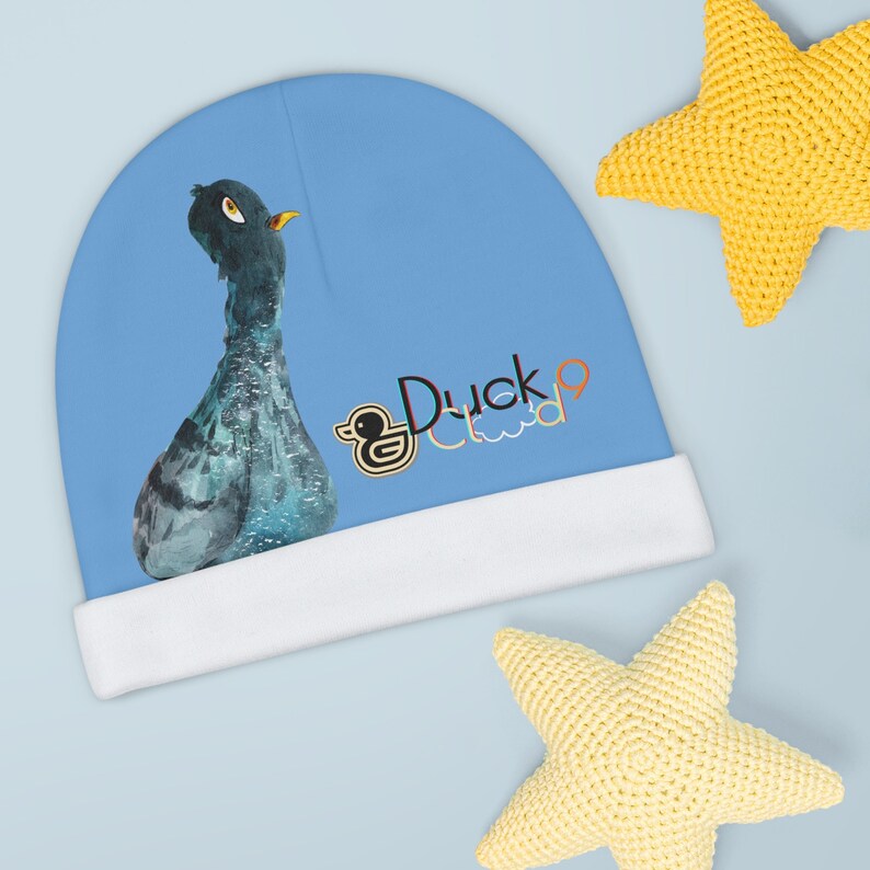 Puede incluir: Un gorro azul con borde blanco presenta un pato de dibujos animados y el texto "Duck Cloud" en letras de colores.