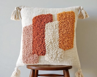 Funda de almohada bohemia de algodón crudo con borlas en naranja, óxido y rosa.