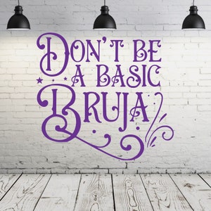 May include: Purple text on a white brick wall that reads "Don't be a basic bruja". The text is in a decorative font with swirls and stars.
