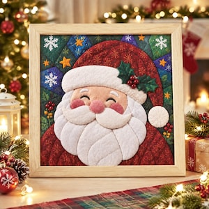Könnte beinhalten: Ein quadratisches, gerahmtes Wandbild aus Stoff mit einem gesteppten Weihnachtsmann-Gesicht, weißem Bart, Schnurrbart und Mützenbesatz. Der Hintergrund besteht aus einem blau-grünen Patchwork-Muster mit gelben Sternen und weißen Schneeflocken.