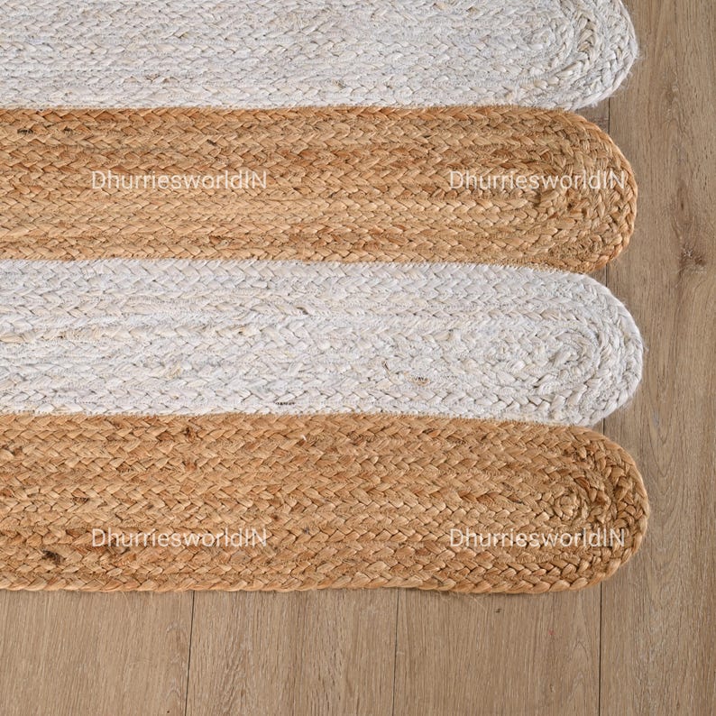 May include: A jute rug with alternating stripes of natural jute and white. The rug has a rounded shape and is woven with a simple, textured pattern.