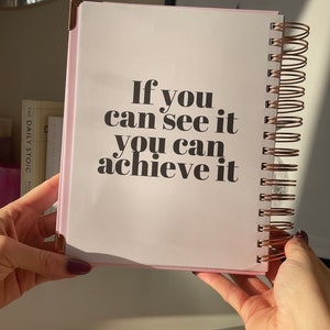 May include: A pink spiral bound notebook with the text "If you can see it you can achieve it" printed in black.