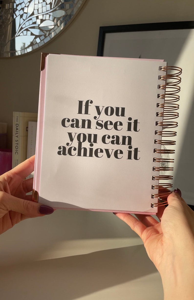 May include: A pink spiral bound notebook with the text "If you can see it you can achieve it" printed in black.