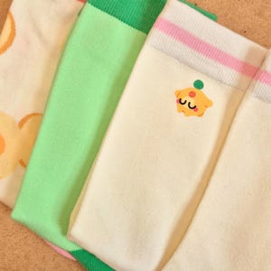 K&ouml;nnte beinhalten: Vier Paar bunte Socken. Ein Paar hat einen rosa Bund und Ferse, ein anderes einen gr&uuml;nen Bund und ein drittes ein Cupcake-Motiv. Die Socken sind cremefarben, gr&uuml;n und rosa.