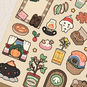 May include: A sheet of decorative stickers featuring various illustrated objects. The stickers include a pumpkin, a dog, a pie, a can of mustard, a book, a bow, and a door with a dog-shaped wreath. The color palette is primarily beige, brown, and orange.