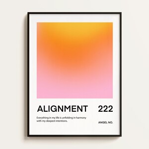 May include: A black framed print with a pink and orange gradient background. The text "ALIGNMENT 222" is printed in black at the bottom of the print. The text "Everything in my life is unfolding in harmony with my deepest intentions." is printed in black below the number. The text "ANGEL NO." is printed in black below the text.