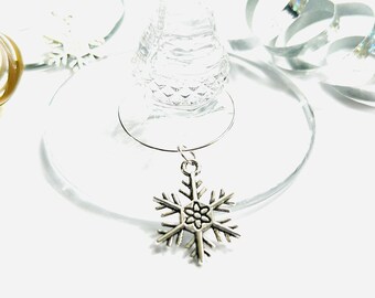 May include: Silver snowflake wine glass charm. The charm is attached to a silver ring that can be placed around the stem of a wine glass.