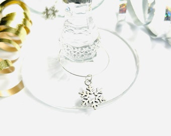 May include: Silver snowflake wine glass charm. The charm is attached to a silver wire ring.