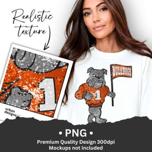 Peut inclure: Sweat-shirt blanc avec un motif de bouledogue à paillettes tenant un drapeau avec l'inscription "BULLDOGS". Le bouledogue porte un maillot avec le numéro "1". Un échantillon de design montre des paillettes orange et argentées. Le texte "Realistic texture" est inclus.