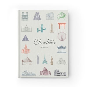 May include: A white travel journal featuring the text "Charlotte's Travels" and illustrations of famous landmarks from around the world, including the Eiffel Tower, the Great Wall of China, and the Taj Mahal.