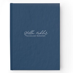 May include: A dark blue notebook with the text "Stella Kohler" and "Technology Sorcerer" in white lettering.
