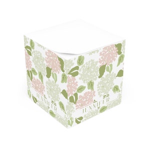 May include: A white square notepad with a floral design featuring pink and green hydrangeas. The notepad has the name "Jennifer" printed on two sides.