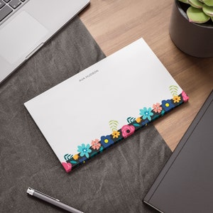 May include: White stationery with a floral border in shades of pink, blue, green, and yellow. The name "AVA HUDSON" is printed in black at the top of the page.