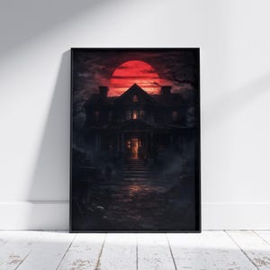 Framed haunted mansion poster displayed in a moody interior setting, showing an eerie house under a deep red moon with glowing windows and overgrown surroundings. This gothic wall art creates a mysterious and immersive decor atmosphere.