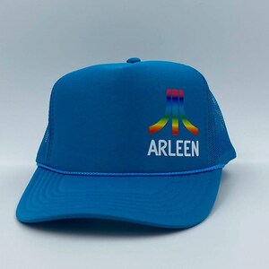 May include: A blue trucker hat with a white rope brim and mesh back. The front features a colorful logo and the name "ARLEEN" in white. The hat is a classic style, suitable for casual wear and outdoor activities.