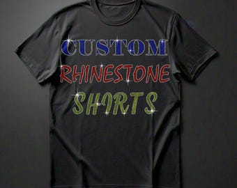 May include: Black t-shirt with the words "CUSTOM RHINESTONE SHIRTS" in colorful rhinestones.