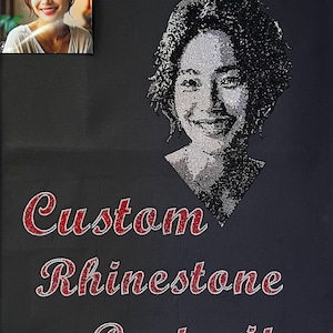Może przedstawiać: Czarne tło z niestandardowym portretem kobiety uśmiechającej się, wykonanym z kryształków. Tekst "Custom Rhinestone Portraits" jest napisany czerwonymi kryształkami pod portretem.
