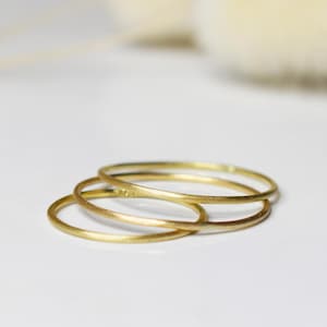 Può includere: Tre anelli impilabili in oro, ognuno con una superficie liscia e arrotondata.