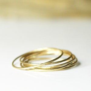 May include: A stack of thin gold rings, each with a slightly different width, creating a layered effect.