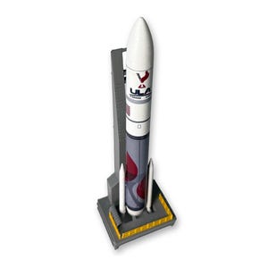 Könnte beinhalten: Ein Modell einer Rakete mit weißer Nase und grau-rotem Körper, die auf einer grauen Startplattform steht. Die Rakete trägt das ULA-Logo und wird von zwei weißen Boostern flankiert. Die Startplattform hat gelbe Akzente.