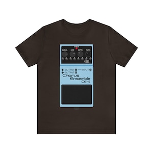 May include: A brown t-shirt with a light blue graphic of a Chorus Ensemble CE-5 effects pedal. The design includes knobs, inputs, outputs, and the text "Chorus Ensemble CE-5".