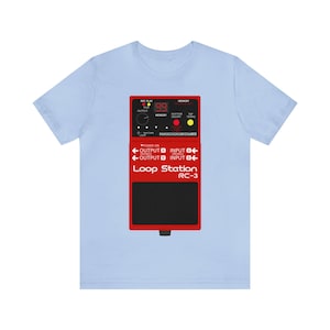 May include: Light blue t-shirt featuring a red Loop Station RC-3 graphic. The graphic includes text such as "REC PLAY", "MEMORY", "OUTPUT", and "INPUT". The design also shows a digital display and various buttons.