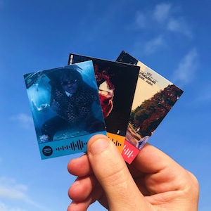 May include: Three colourful cards with a person on one card, a house on another card, and trees on the third card. The cards have a QR code and the text "My Neighbourhood" on one card, "Beautiful" on another card, and "J. Jones" on the third card.