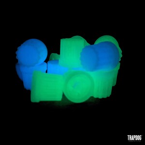 Peut inclure: Collection de bouchons de bouteille fluorescents de couleur n&eacute;on. Les bouchons sont dans des tons de bleu et de vert, avec diverses formes et designs. L'image est sur fond noir, mettant en valeur les couleurs vives des bouchons.