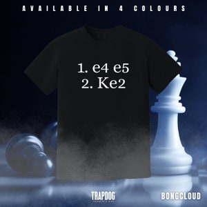 May include: Black t-shirt with white text that reads "1. e4 e5 2. Ke2". The shirt is on a chessboard with a white chess piece in the background.