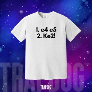 May include: White t-shirt with black text that reads "1. e4 e5 2. Ke2!"  TRAPDOG is printed in black at the bottom of the shirt.